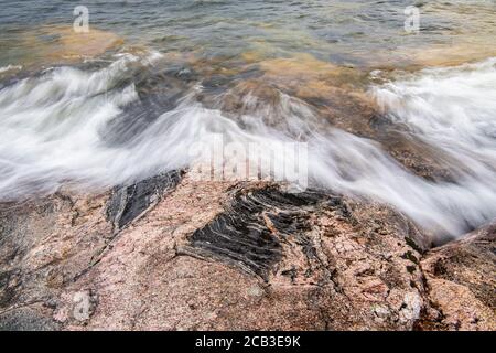 Fai un'ondata di azione sugli affioramenti di granito lungo il lago Superior a Katherine Cove, Lake Superior Provincial Park, Ontario, Canada Foto Stock