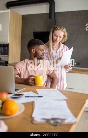 Giovani razza mista coppia sposata con colazione al mattino in cucina e utilizzando laptop. Shopping online. Foto Stock