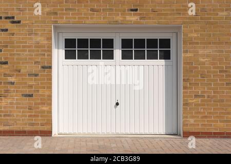 Look classico, porte da garage a battente laterali bianche, su una casa di nuova costruzione. Hertfordshire. REGNO UNITO Foto Stock