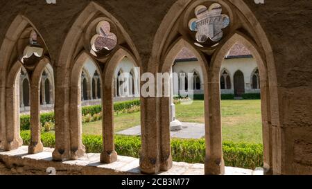 Corridoio ombreggiato con colonne con vista su un monastero cortile Foto Stock