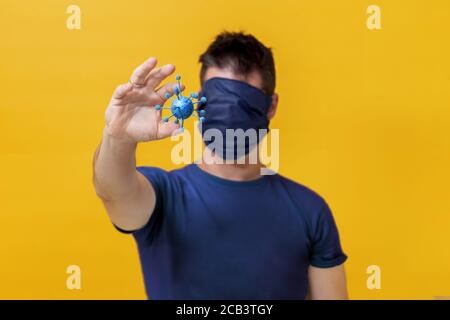 Giovane maschio con maschera medica su tutto il viso tenendo Illustrazione 3D della cellula batterica del coronavirus Foto Stock