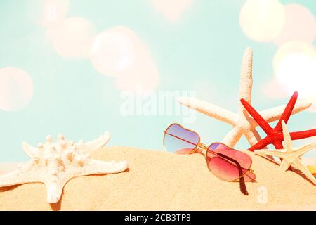 Occhiali da sole con stelle marine sulla spiaggia di sabbia Foto Stock