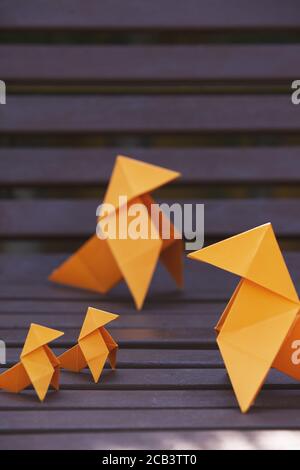 Immagine verticale di una famiglia di figure origami su un parco banco Foto Stock
