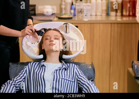 giovane bella donna tintura capelli in salone di bellezza moderno, professionale parrucchiere lavaggio e tintura capelli donna Foto Stock