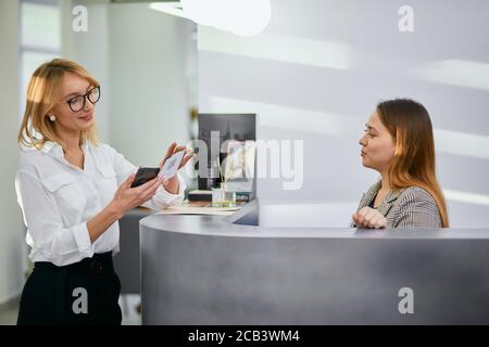 amministratore cordiale e bellissimo cliente caucasico in salone di bellezza, guardarsi l'un l'altro e sorridere, personale cordiale in salone di bellezza. Giovane donna camma Foto Stock