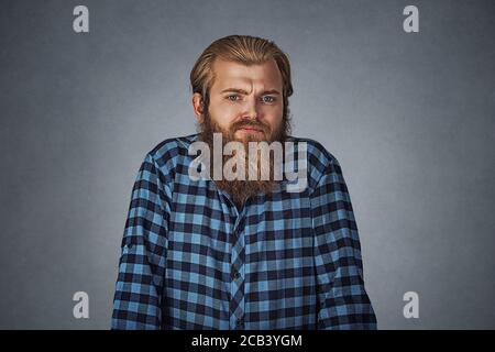 Ignoranza e arroganza. Giovane uomo bearded shrugging spalle che si preoccupa così che cosa. Hipster maschio con barba in camicetta a scacchi blu color grigio isolato Foto Stock