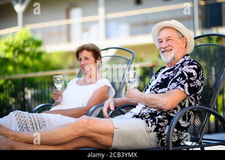 Coppia senior che tiene vino all'aperto in vacanza, rilassante. Foto Stock