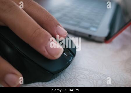 Messa a fuoco selettiva di una mano maschile utilizzando un wireless mouse del computer Foto Stock