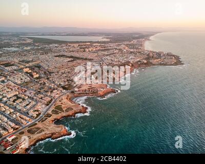 Foto panoramica aerea del paesaggio urbano di Torrevieja, costa rocciosa Mar Mediterraneo all'alba, lago salato o Las Salinas, vista dall'alto. Pro Foto Stock