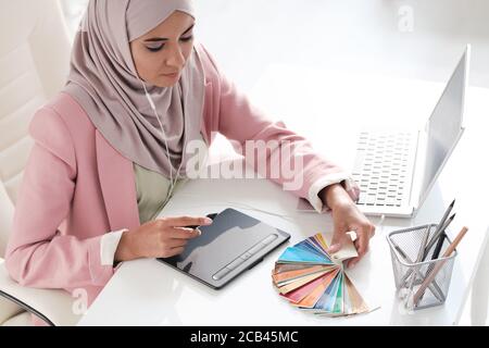 Sopra la vista del giovane grafico arabo concentrato scegliendo il colore per la progettazione in ufficio Foto Stock