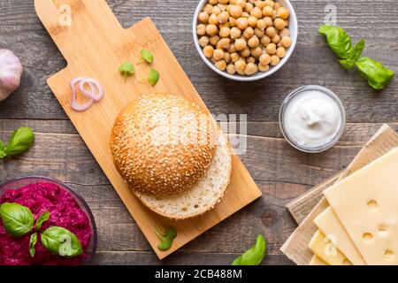 Vista dall'alto ingredienti per cucinare hamburger vegani su fondo di legno scuro piatto. Foto Stock