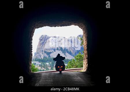 Guida in moto attraverso un tunnel sulla Needles Highway con vista sul Monte Rushmore nel Custer state Park, South Dakota Foto Stock