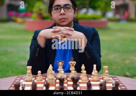 Una ragazza indiana che gioca a scacchi in attesa che l'avversario giochi e che pensa ansiosamente alla sua prossima mossa. Concetto - idea, strategia Foto Stock