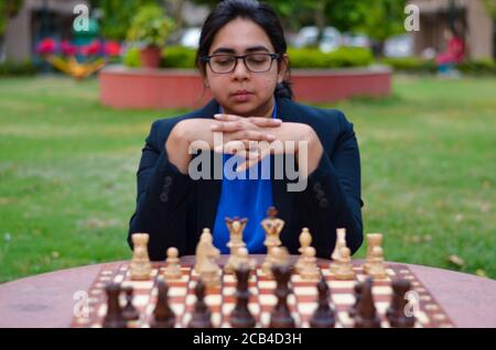 Una ragazza indiana che gioca a scacchi in attesa che l'avversario giochi e che pensa ansiosamente alla sua prossima mossa. Concetto - idea, strategia Foto Stock