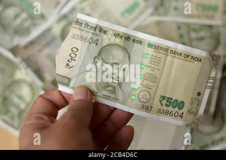 Una mano di donna che tiene una lacerata nuova RS 500 Rupees Note in valuta indiana che mostrano Mahatma Gandhi stampato sulla nota contro uno sfondo bokeh con un sacco di Foto Stock