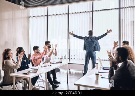 felici colleghi che applaudono il leader durante un incontro: felicità, fortuna, successo Foto Stock