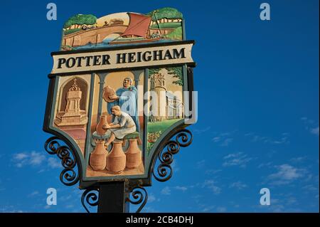 Segno ornato villaggio per Potter Heigham, Norfolk, contro un cielo blu Foto Stock