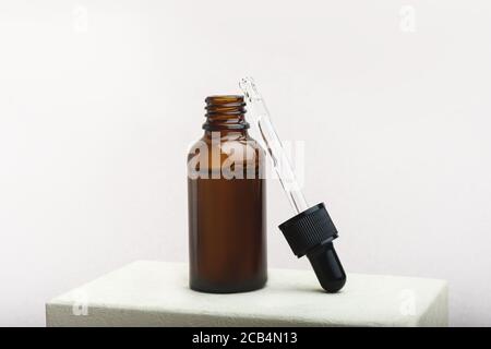 Flacone contagocce in vetro aperto su sfondo beige. Foto Stock