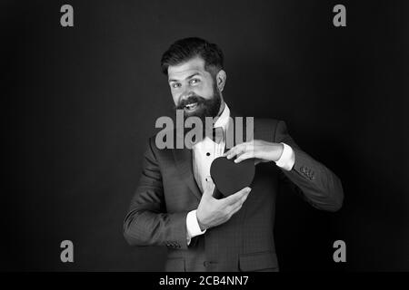 Posso aiutarla. Giornata mondiale del cuore. Brutale hipster barbuto in abito formale. Uomo d'affari in cravatta di prua. Assistenza sanitaria. Decorazione di giorno di San Valentino. Tuxedo uomo con cuore rosso. Festa di festa. Concetto di amore. Foto Stock