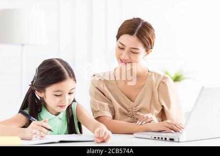 La madre sta lavorando e insegnando la sua figlia che fa il lavoro domestico Foto Stock