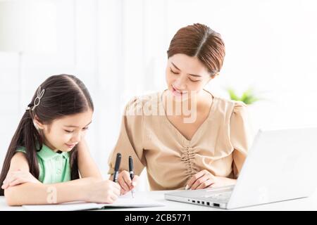 La madre sta lavorando e insegnando la sua figlia che fa il lavoro domestico Foto Stock