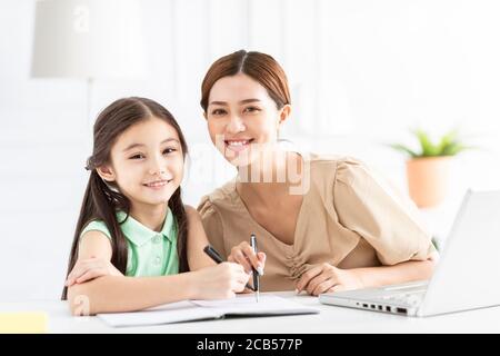 La madre sta lavorando e insegnando la sua figlia che fa il lavoro domestico Foto Stock