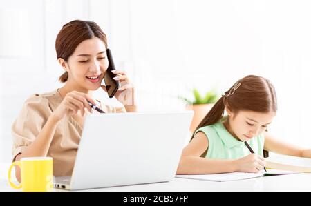 Madre che lavora a casa e insegna a sua figlia che fa casa lavoro Foto Stock