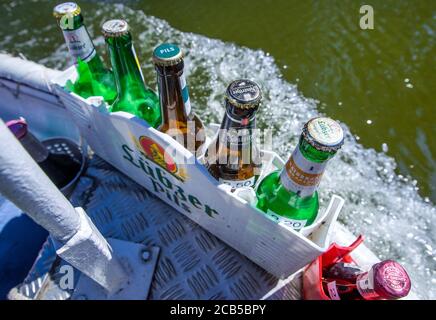 Diemitz, Germania. 06 agosto 2020. Nella 'finestra salta' sulla prua del suo chiosco d'acqua, Jens Winkelmann mostra le birre fredde in offerta sul lago di Vilzsee. Fornisce ai vacanzieri su case galleggianti, yacht e canoe ghiaccio, bevande fredde o pesce appena affumicato. Ogni giorno, durante la stagione, viaggia fino a 80 chilometri lungo i corsi d'acqua e il lago al confine con lo stato del Brandeburgo e del Meclemburgo. Il Brandeburgo ha convertito la sua vecchia chiatta lunga quattro metri in una sorta di "consumo galleggiante" con un congelatore e scatole di conservazione del fresco. Credit: Jens Büttner/dpa-Zentralbild/dp/dpa/Alamy Live News Foto Stock