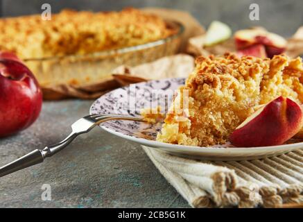 Torte fatte in casa, un pezzo di torta su un piatto con pesche e pere su cemento grigio-blu. Primo piano Foto Stock