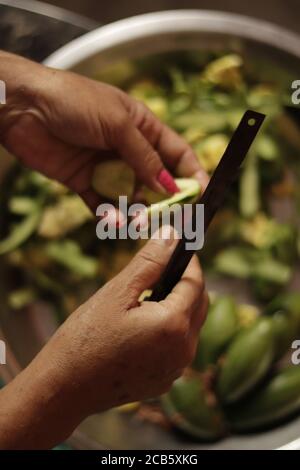 Madre indiana che taglia verdure verdi con coltello tagliente affilato Chiudi su Foto Stock