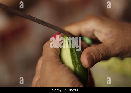 Madre indiana che taglia verdure verdi con coltello tagliente affilato Chiudi su Foto Stock