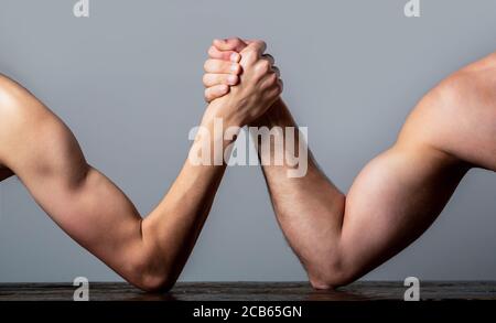 Braccio wrestling. Braccio uomo molto muscled che lotta un uomo debole puny. Braccio wrestling mano sottile e un grande braccio forte in studio. Due mani dell'uomo si sono aggrappate al braccio Foto Stock
