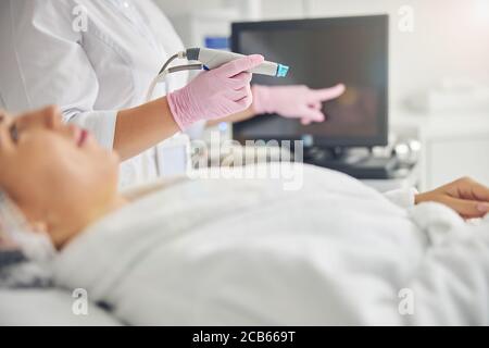 Cosmetician in guanti sterili che ribalta il touch screen Foto Stock