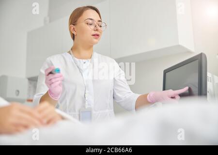 Medico che regola i parametri di trattamento sul touchscreen Foto Stock