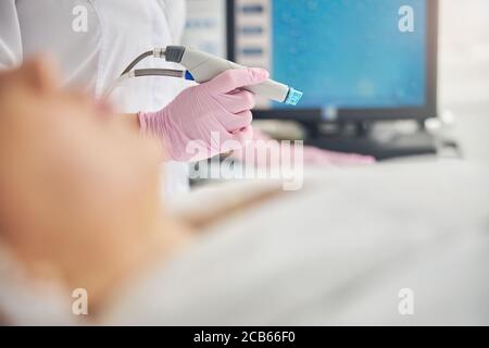 Medico in un camice di laboratorio che tiene un dispositivo di bellezza Foto Stock