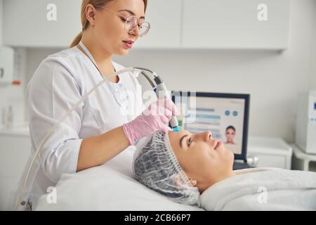 Donna che viene trattata da un dermatologo professionista Foto Stock