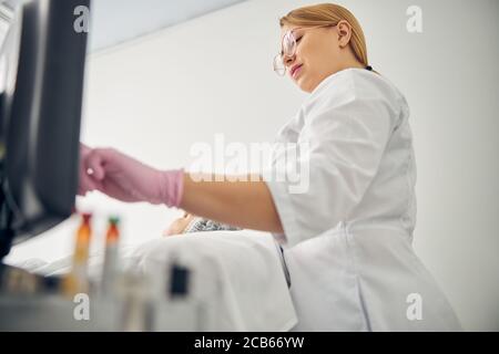 Estetista in occhiali iniziando una procedura cosmetica Foto Stock