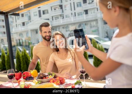 Ragazza dai capelli giusti che fa l'immagine dei suoi parennts felici Foto Stock