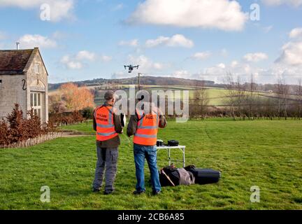Due fotografi che volano un drone con una fotocamera in un Ampio giardino di campagna nel Cotswolds Foto Stock