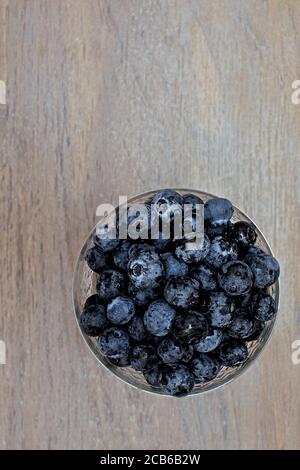 mirtilli appena raccolti in una piccola ciotola su un legno superficie Foto Stock