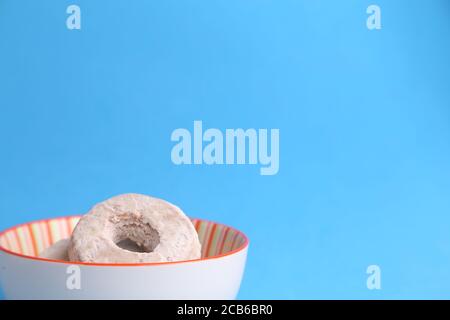Primo piano di bagel fatti in casa in una ciotola di fronte uno sfondo blu luminoso Foto Stock