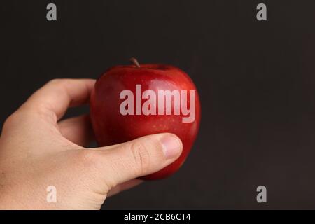 Primo piano di una mano che tiene un rosso brillante apple Foto Stock
