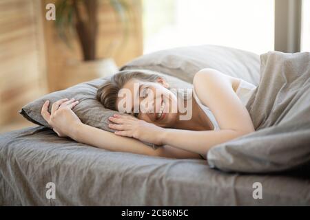 Buongiorno. Donna sorridente sdraiata in un comodo letto dopo il risveglio, all'interno Foto Stock