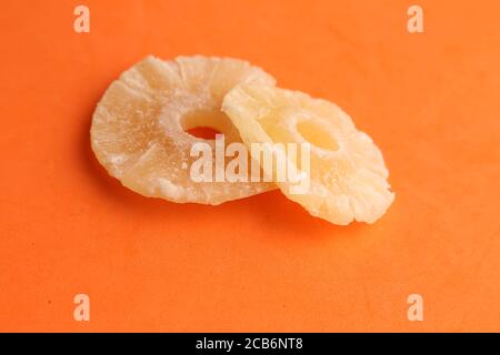 Colpo di primo piano di fette di ananas essiccate isolate su un arancio sfondo Foto Stock