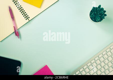 Sfondo minimalista e a spirale notebook o Spring notebook con cancelleria Ad esempio penna e etichetta adesiva a colori e tastiera del computer E tablet e Tr Foto Stock