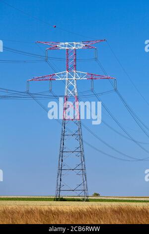 Piloni elettrici nella campagna francese sotto un cielo blu chiaro. Foto Stock