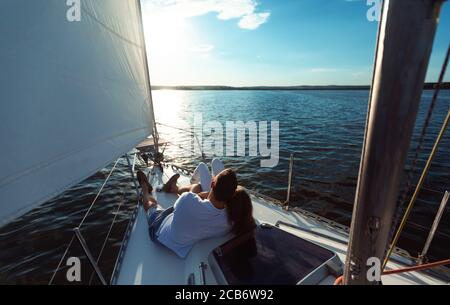 Coppia rilassante su Yacht sdraiato sulla terrazza all'aperto, vista posteriore Foto Stock