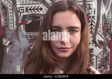 Ritratto di una giovane donna sorridente di fronte a un parete con poster strappati Foto Stock