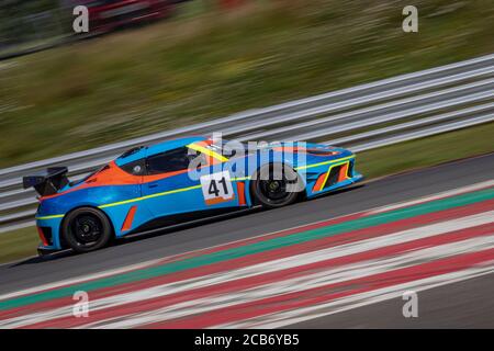 Una panoramica di una vettura da corsa blu e arancione mentre la pista è in pista. Foto Stock