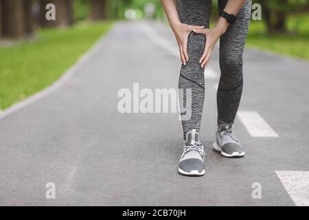 Trauma del ginocchio. Unriconoscable Woman Jogger Hut la sua gamba durante la corsa all'aperto Foto Stock